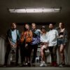 Fashionable group of six adults posing stylishly in an urban underground setting.