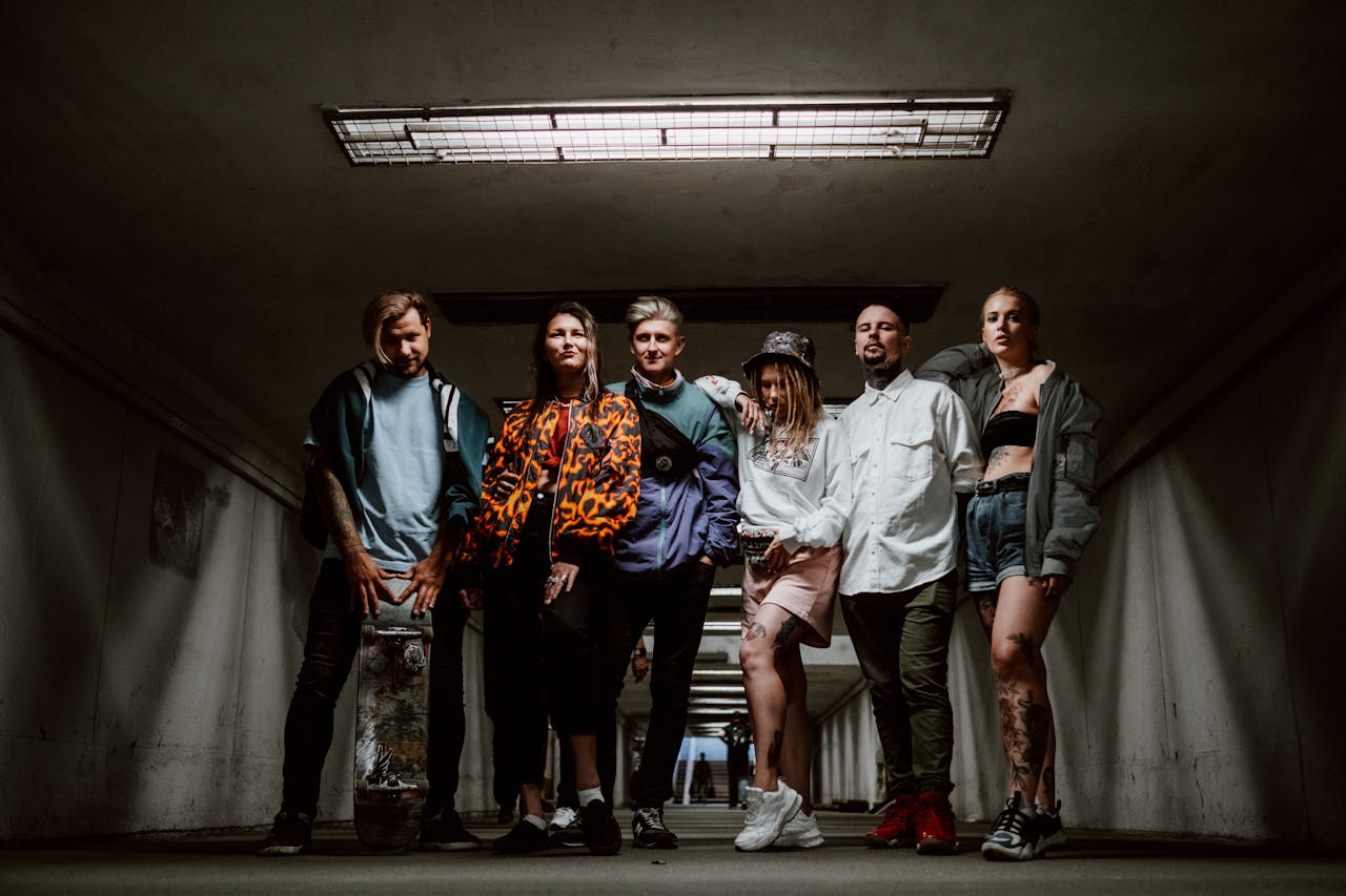 Fashionable group of six adults posing stylishly in an urban underground setting.