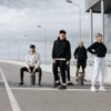 Four adults posing stylishly in sportswear in an urban street setting.